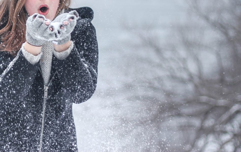 雪を手に持ち飛ばす女性